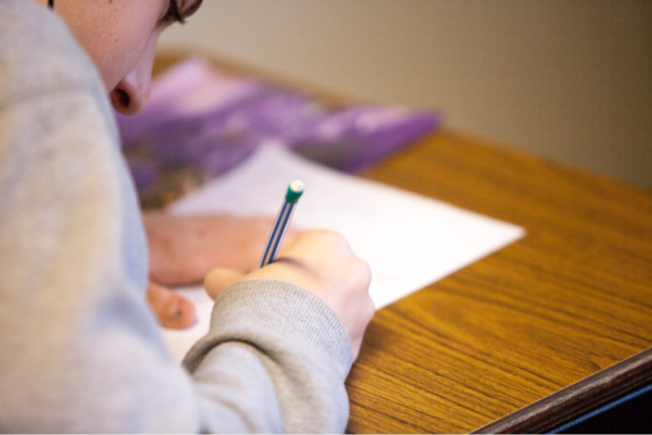 Jongen met pen schrijvend op papier